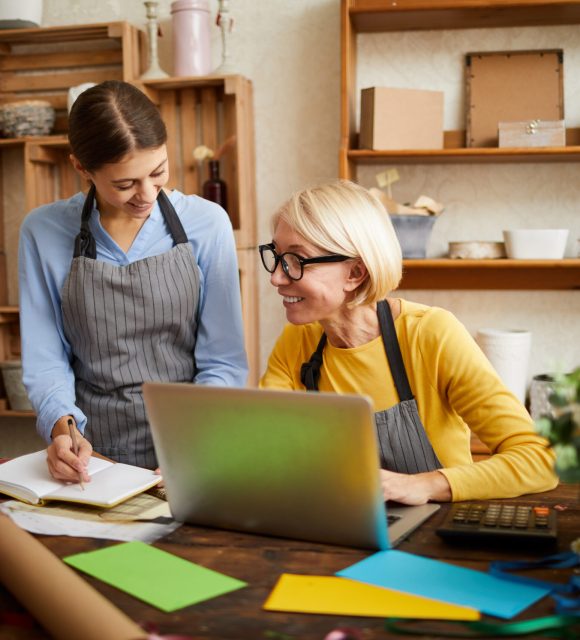 Portrait of two businesswomen using laptop while managing shop, copy space