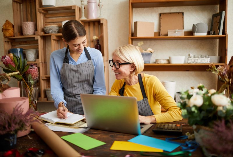 Portrait of two businesswomen using laptop while managing shop, copy space