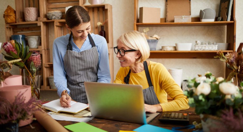 Portrait of two businesswomen using laptop while managing shop, copy space