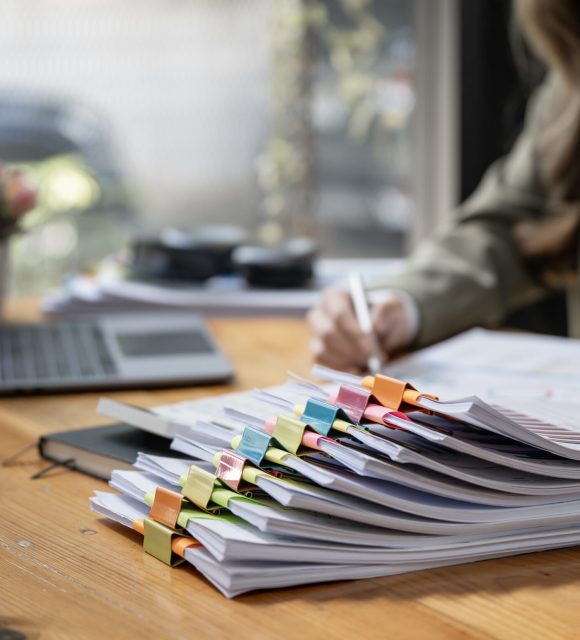 Business Documents concept : Businesswoman working in Stacks of paper files for searching and checking unfinished document achieves on folders papers